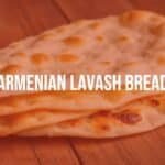 Traditional Armenian lavash bread, freshly baked, thin and soft, on a wooden table with rustic background, warm golden tones, realistic.